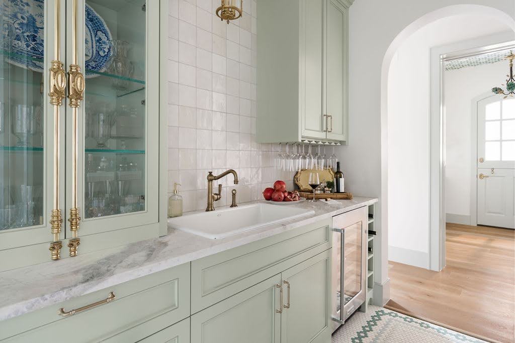 Custom home beverage station with elegant cabinetry, marble countertops, and brass fixtures